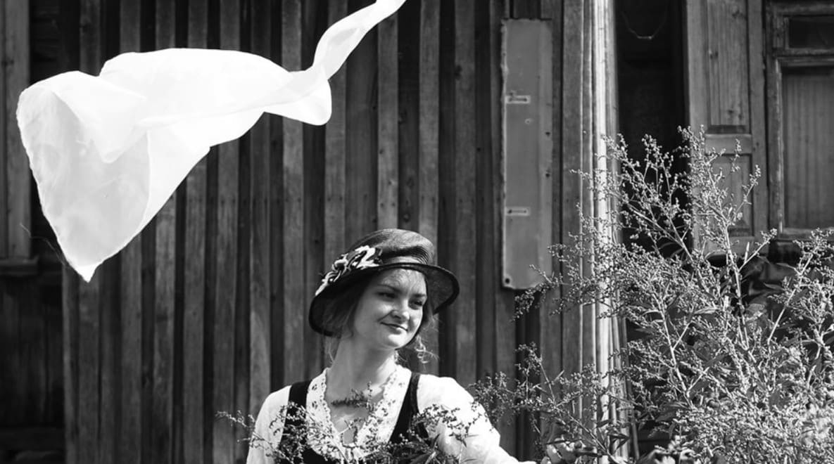 Дзяучына любуецца кветкамi, над её ляцiць кавалачак тонкай тканiны